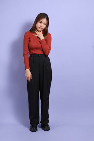 The young Southeast Asian woman in casual clothes, standing against a purple background.