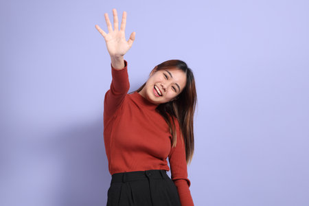 The young Southeast Asian woman in casual clothes, standing against a purple background.の写真素材