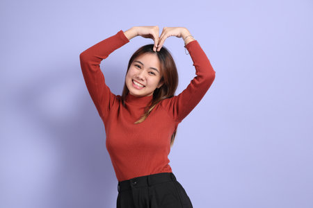 The young Southeast Asian woman in casual clothes, standing against a purple background.の写真素材
