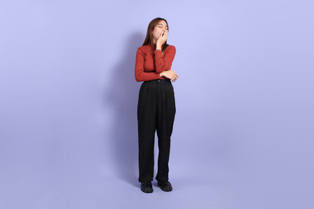 The young Southeast Asian woman in casual clothes, standing against a purple background.