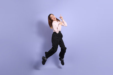 A young Southeast Asian woman in business clothes, standing against a purple background.