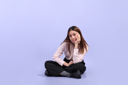 A young Southeast Asian woman in business clothes, sitting against a purple background.の写真素材