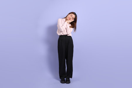 A young Southeast Asian woman in business clothes, standing against a purple background.