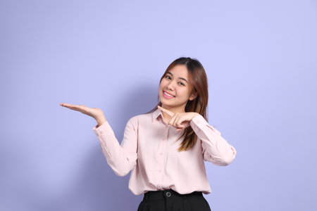 A young Southeast Asian woman in business clothes, standing against a purple background.の写真素材