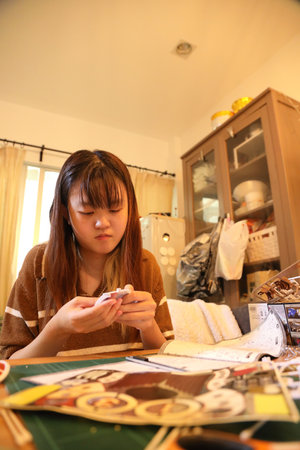 The East Asian woman assembling a plastic model toy in the living room by herself.