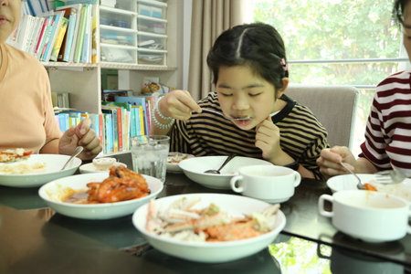 An East Asian girl is having lunch with her parents in the dining room.の写真素材