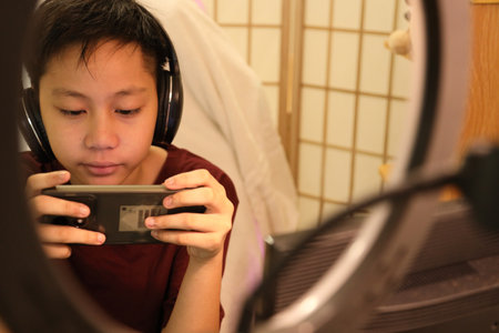 The boy is playing an online game on his smartphone.