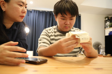 The teenage boy is helping his mother calculate the monthly expenses from the receipts.