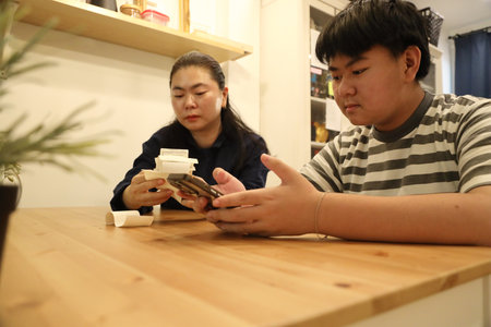 The teenage boy is helping his mother calculate the monthly expenses from the receipts.