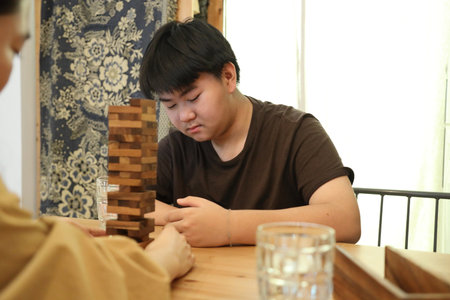 The boy is playing the stack wooden tower game with his mother.