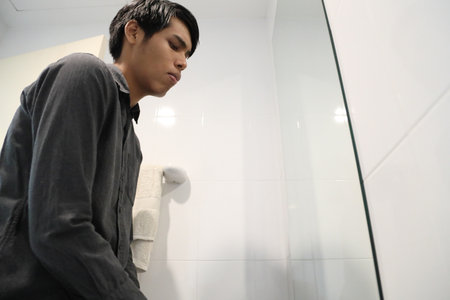 The Southeast Asian man is washing his face and styling his hair in the bathroom.