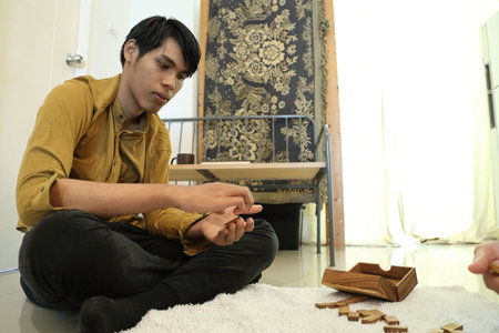 The Southeast Asian man is playing a domino game with his friends.