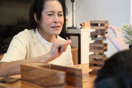 The Southeast Asian boy is playing the stack wooden tower game with his mother.