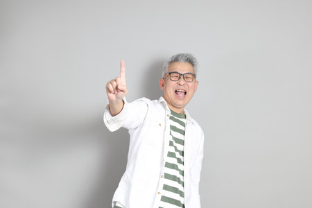 The portrait of an East Asian man with gray hair and glasses, dressed in smart casual clothes,...