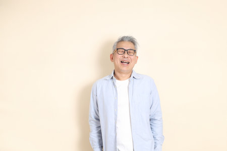 The portrait of an East Asian man with gray hair and glasses, dressed in smart casual clothes,...