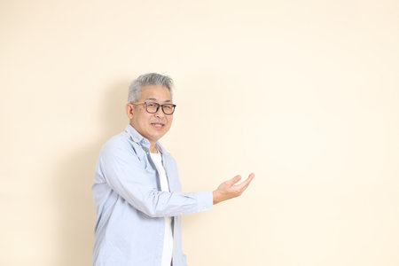 The portrait of an East Asian man with gray hair and glasses, dressed in smart casual clothes.の写真素材