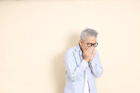 The portrait of an East Asian man with gray hair and glasses, dressed in smart casual clothes,...