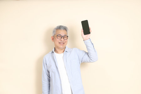 The portrait of an East Asian man with gray hair and glasses, dressed in smart casual clothes,...