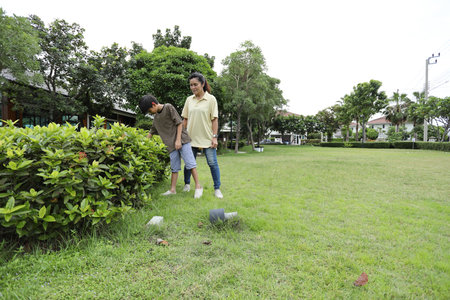 A Southeast Asian single mother spends time with her child in the park, engaging in nature-based...