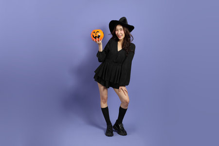 The beautiful East Asian woman in a Halloween costume is standing against a violet background.の写真素材