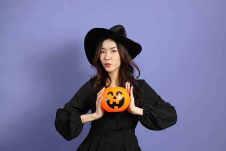 The beautiful East Asian woman in a Halloween costume is standing against a violet background.の写真素材