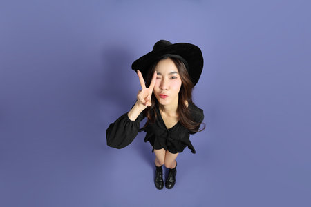 The East Asian woman in a Halloween costume is standing against a violet background.の写真素材