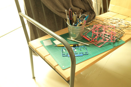 Unassembled plastic model kit parts and hobby tools laid out on a long wooden bench.