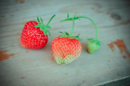 Strawberries red and green on the wood backgroundsの写真素材