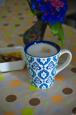 A cup of hot coffee with milk, flowers, honey and book. Romantic background with retro filter effectの写真素材
