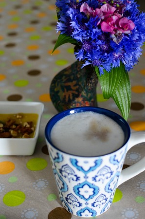 A cup of hot coffee with milk, flowers, honey and book. Romantic background with retro filter effectの写真素材
