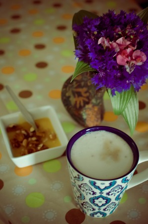 A cup of hot coffee with milk, flowers, honey and book. Romantic background with retro filter effectの写真素材