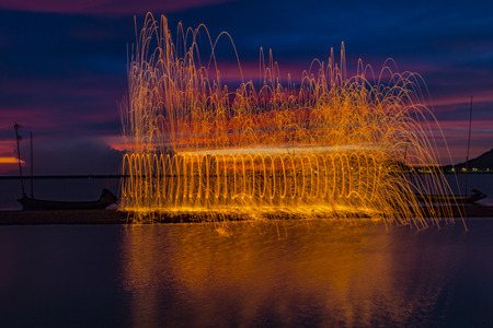 Firework showers of hot glowing sparks from spinning steel wool on the beach.の写真素材