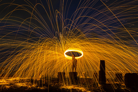 Firework showers of hot glowing sparks from spinning steel wool on the beach.