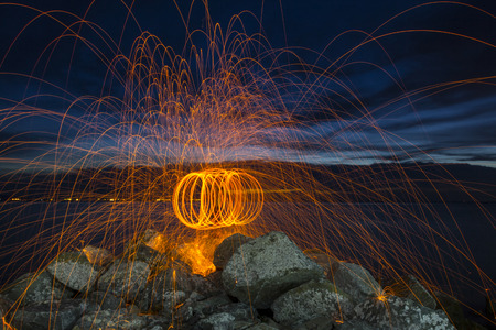 Firework showers of hot glowing sparks from spinning steel wool on the beach.の写真素材