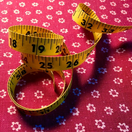 Tape measure on red fabric background
