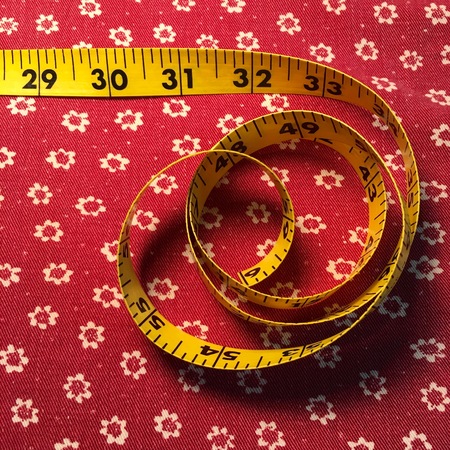 Tape measure on red fabric background