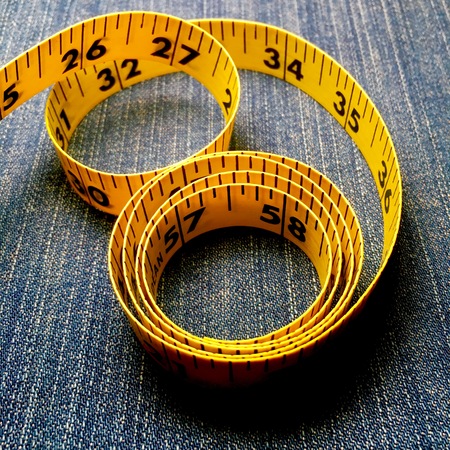 Yellow tape measure on denim backgroundの写真素材