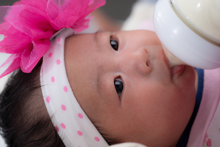 4 weeks old newborn baby feeding from milk bottleの写真素材