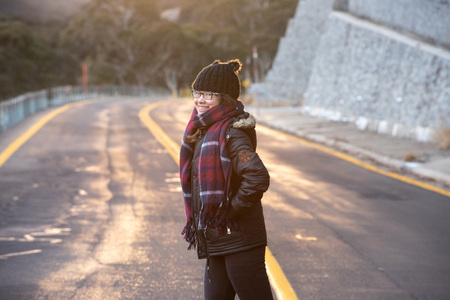 Young woman posing on the road at the crack of dawn with a beautiful sunriseの写真素材