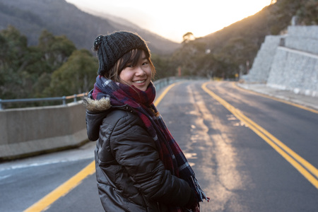 Young woman posing on the road at the crack of dawn with a beautiful sunriseの写真素材