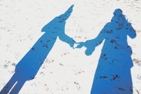 Silhouettes of the shadow of two people on a snow-covered lawn .(Selective focus)の写真素材
