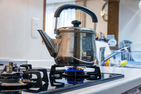 Put metal kettle on a gas stoveの写真素材