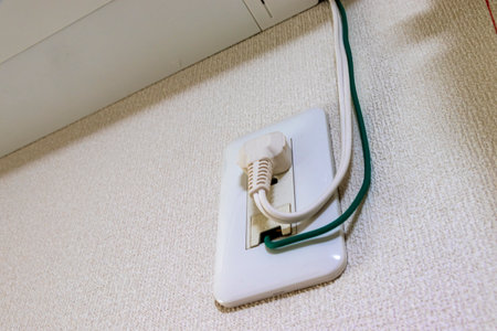 Power plug and ground wire connected to electrical outlet on the wallの写真素材