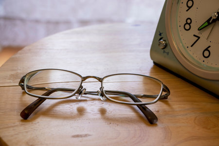 Eyeglasses and clock on the table