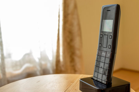 A black phone on the desk by the window