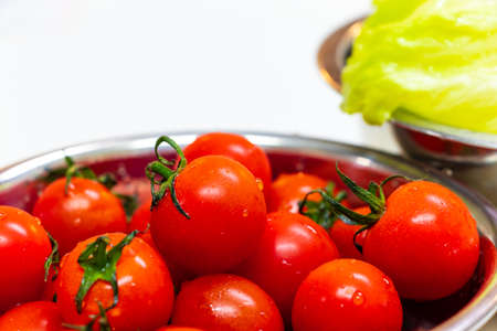 Red cherry tomatoes in a metal bowlの写真素材