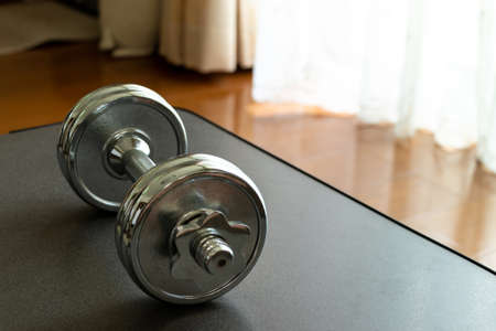 Metal dumbbell on the table by the windowの写真素材