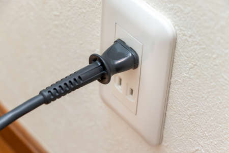 Power plug connected to electric outlet on the wall