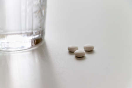 White tablets and a glass of waterの写真素材