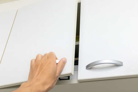Reach out and open the high cabinet door